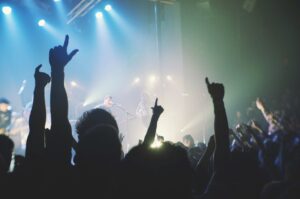 Concert crowd with raised hands under stage lights